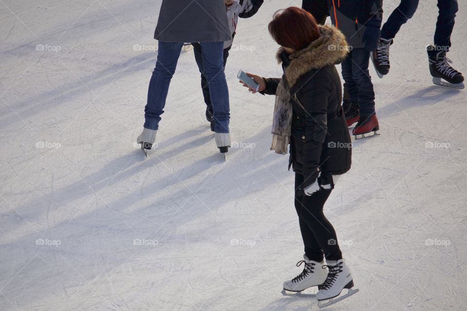 Woman on ice rink holding up cellphone