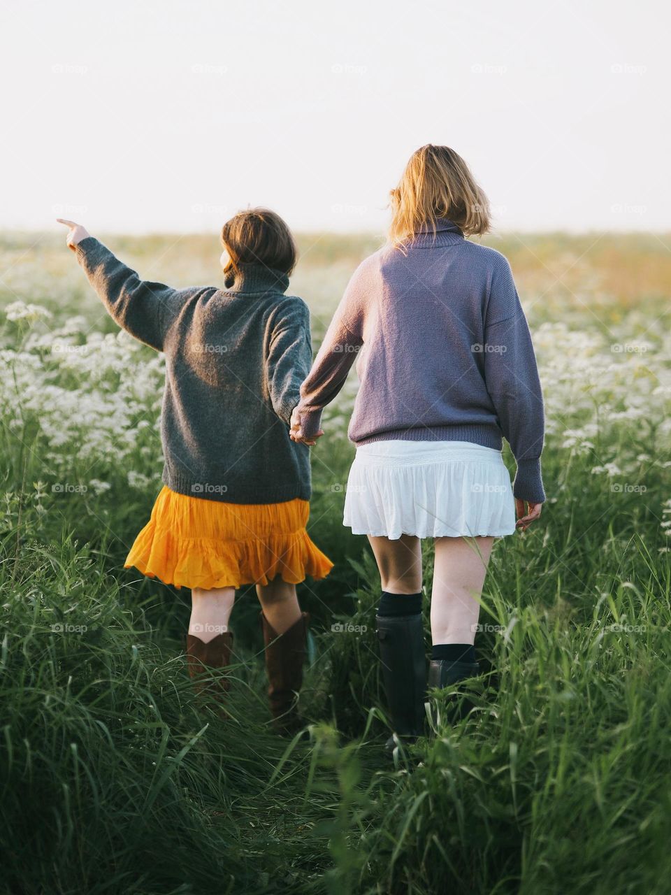 Two young beautiful woman’s walking in field in sunny summer day, portrait of woman