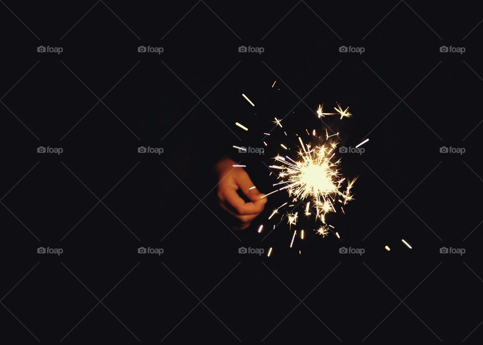 Hand holding a sparkler, playing with light 