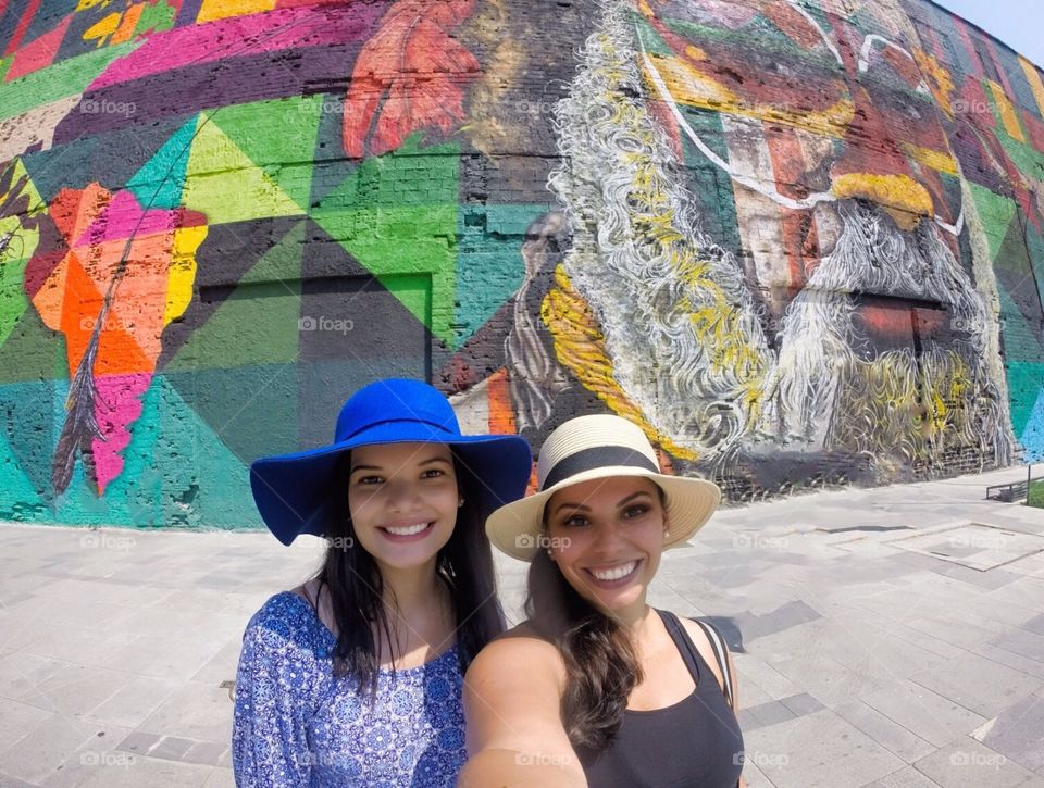 Portrait of two woman against colorful graffiti wall