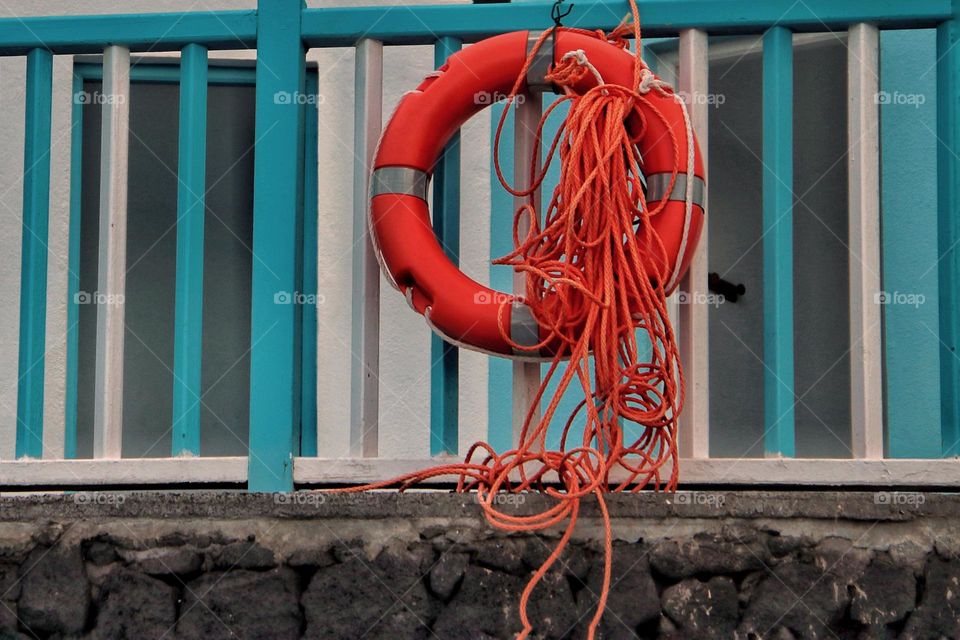 Close-up of an orange colored lifebuoy on blue railing 