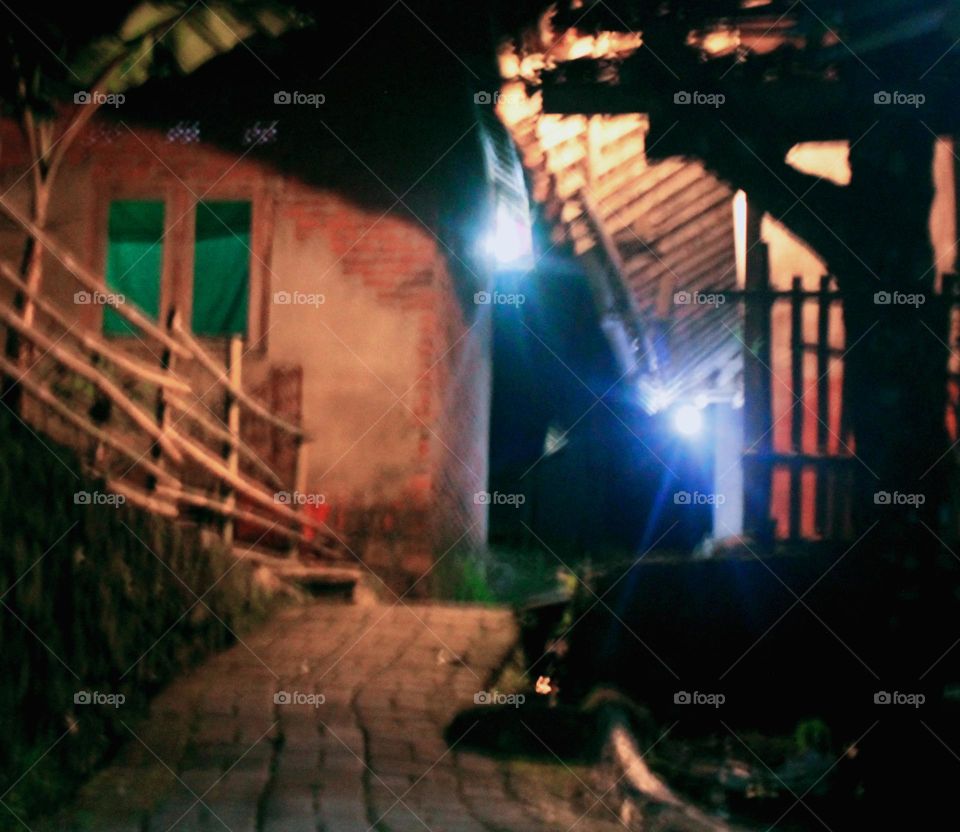 Describing the silence in a village that is only lit by makeshift neon lights that illuminate a narrow alley that night feels cold and chills