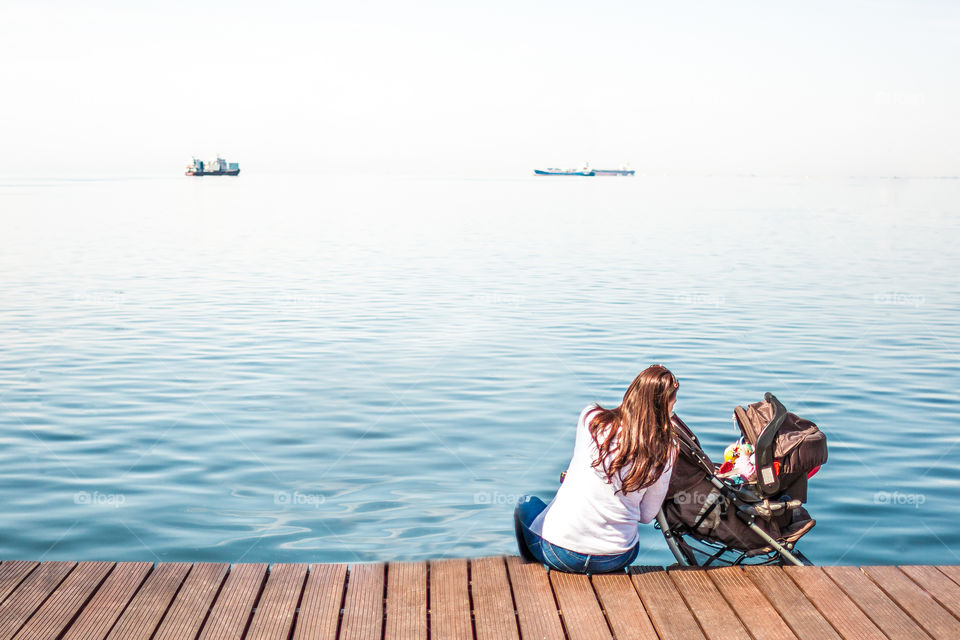 Young Mother Cares Her Baby In Front Of The Sea
