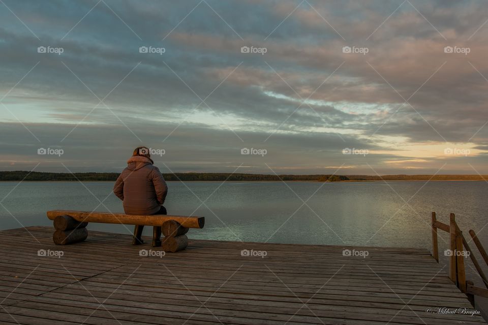 Woman sitting on bench on wooden deck