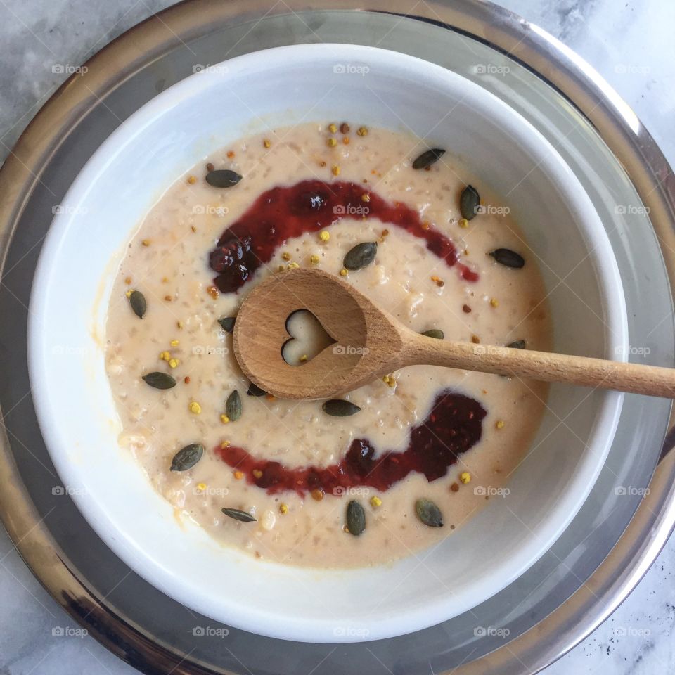 Rice pudding and jam in bowl with jam and heart wooden spoon 