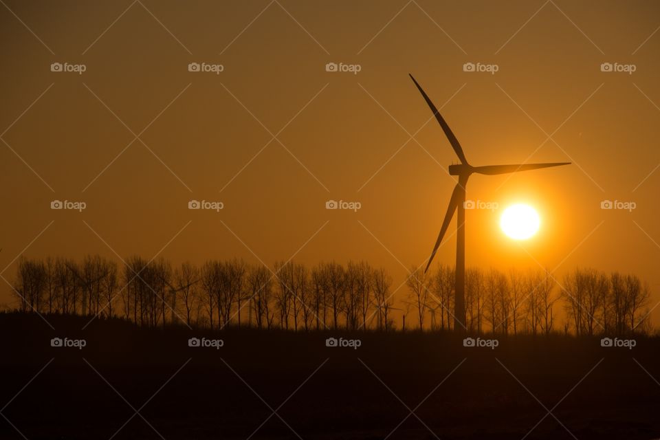 Sunrise in the early morning on a field next to a windmill