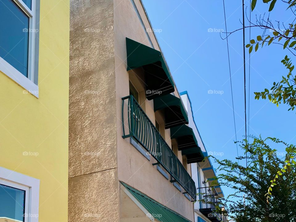 Architectural series of historical building in downtown central eastern Florida town with European style with awnings and tropical trees and blue sky.