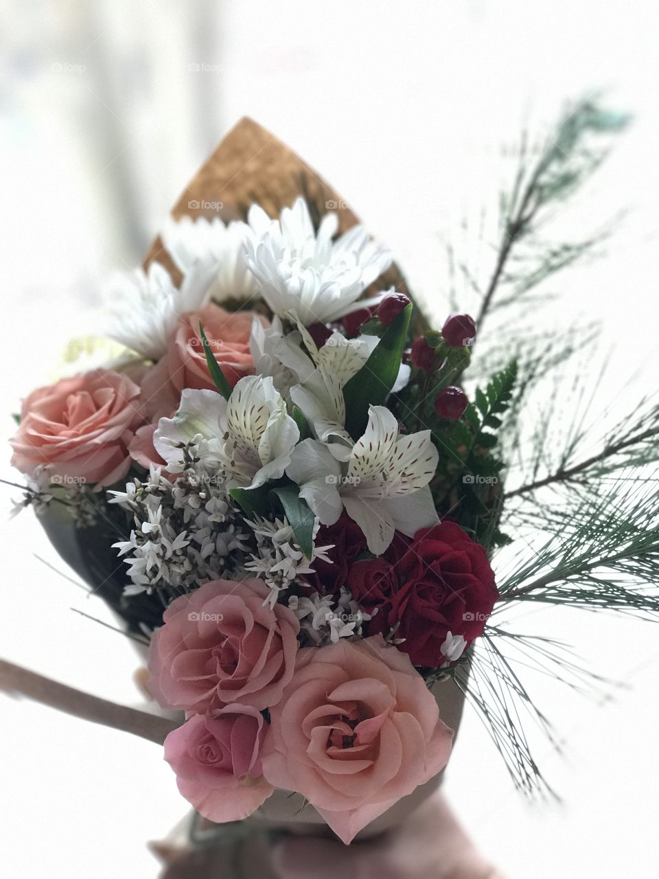 Beautiful bouquet of cool crisp and joyful flowers wrapped in brown paper in white lighting