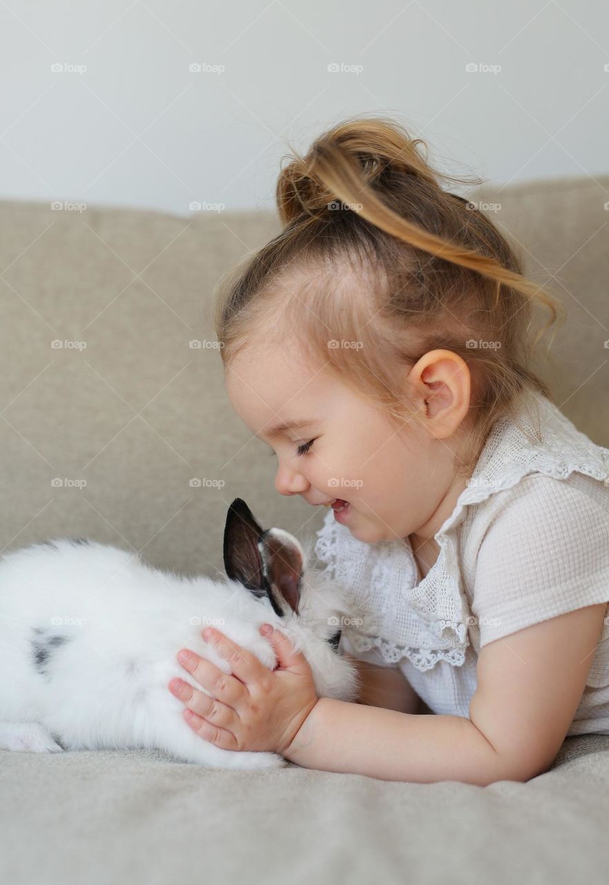 Beautiful little girl with rabbit, Easter come