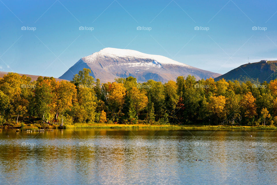 Scenic view of lake by mountains against blue sky