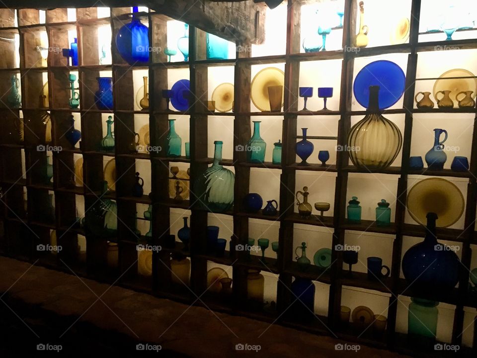 Rows of bottles and plates in square cut shelves. House on the Rock, WI