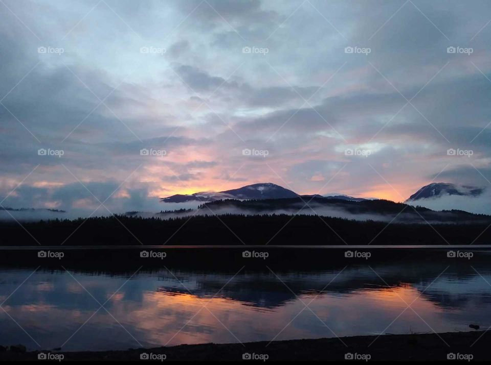 Sun setting behind mountain with its beautiful reflections in the lake