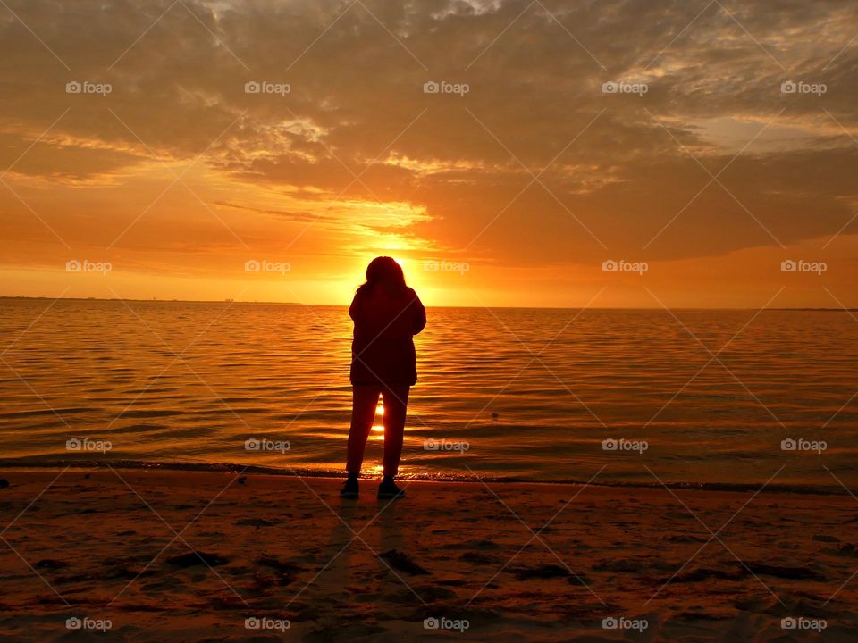 A woman takes photos of the magnificent sunset. Sunsets are fascinating. Sunsets inspire us. Sunsets are the peaceful time of the day. Sunsets are magic!