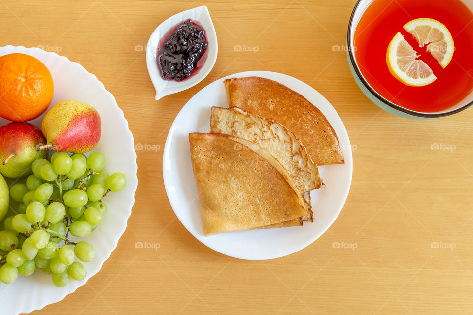 Delicious pancakes, crepes, plate of fruits and citrus gelo. View from above, flatlay