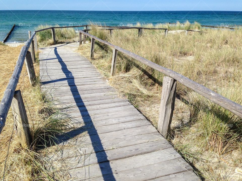 Wooden walkway through the dunes to a sandy Baltic Sea beach in summer sunshine 