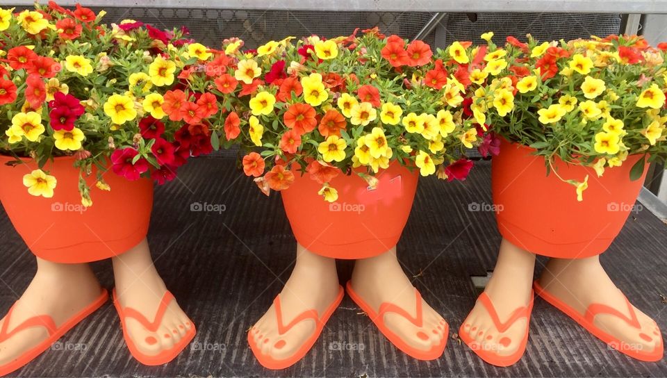 Bright orange flower pots for sale with flip flop feet for stands.