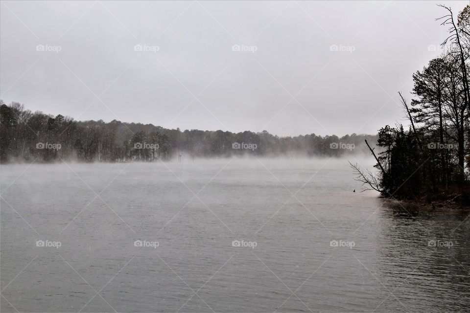 lake steaming during a snowfall in march.