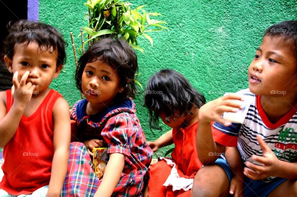 Little asian girls sitting by a sidewalk