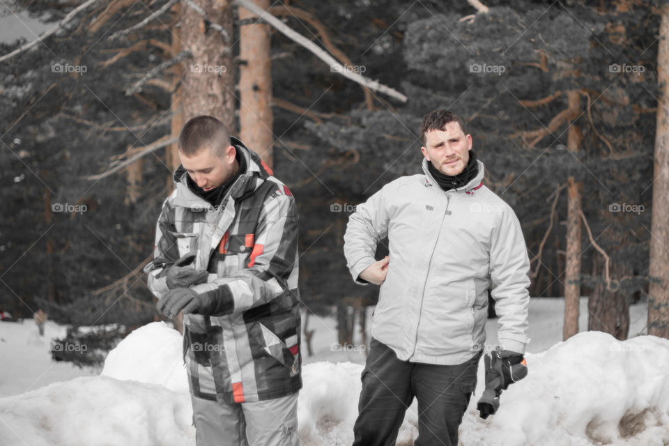 Two boys walking in the snow forest