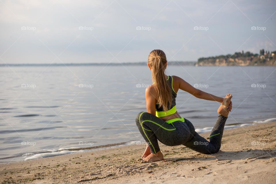 Faceless girl doing legs starching at the beach 