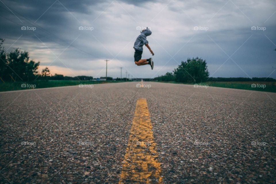time-lapse photo of person jumping at the middle of the road