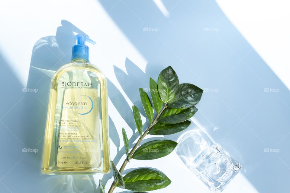 Cosmetic product Bioderma for skin care on a blue background, with a green flower.