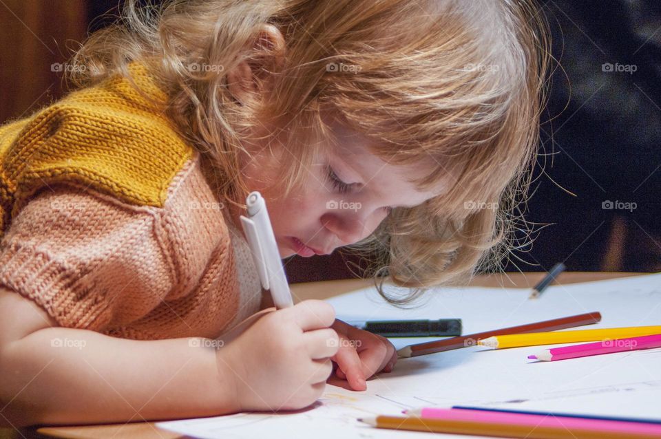 girl draws in an album with pencils