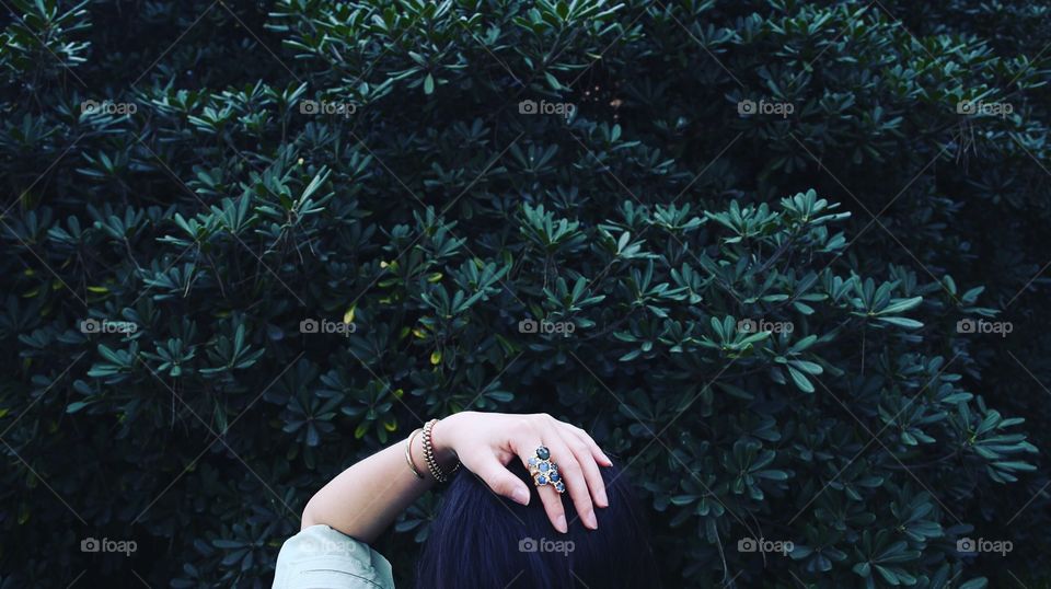 Woman hand on head in front of tree
