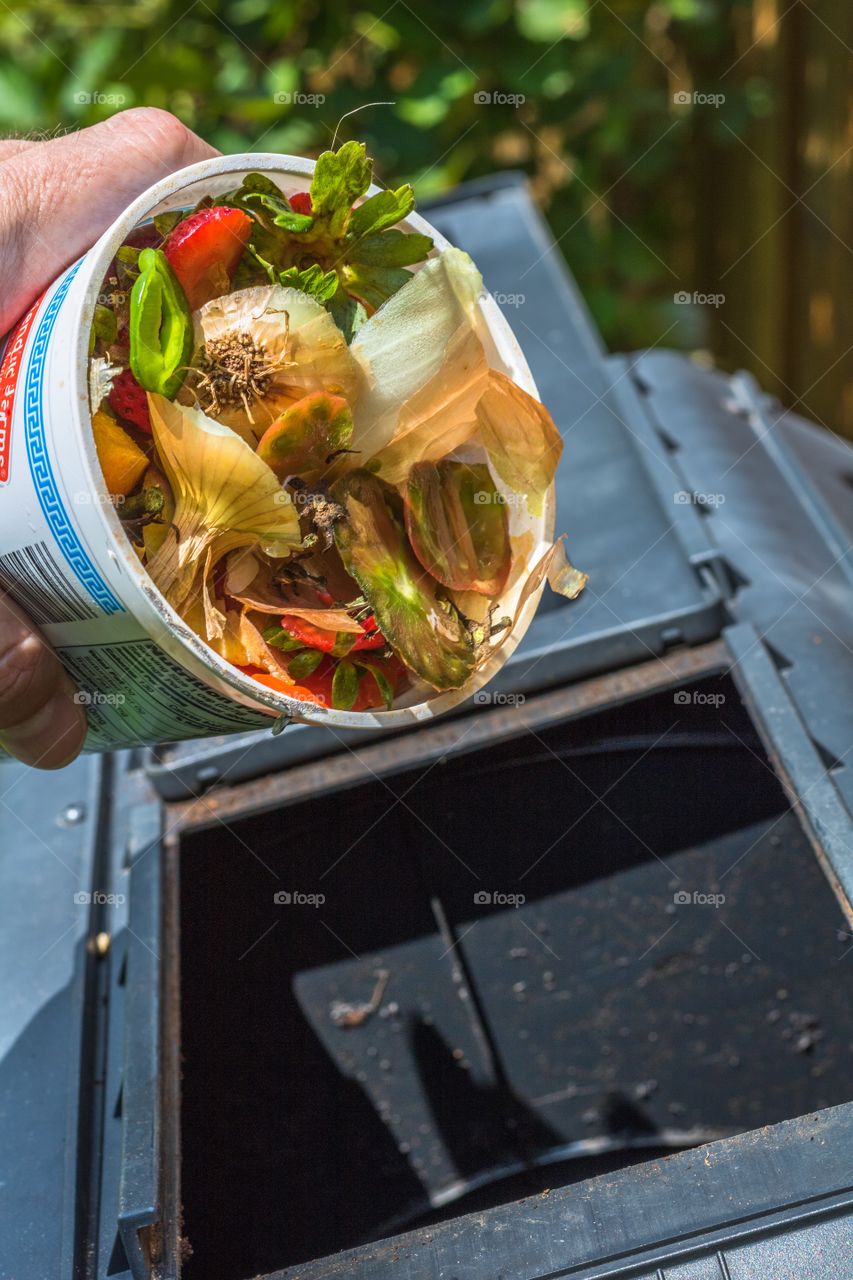 Vertical photo of fruit and vegetable remnants about to be dumped into a compost tumbler
