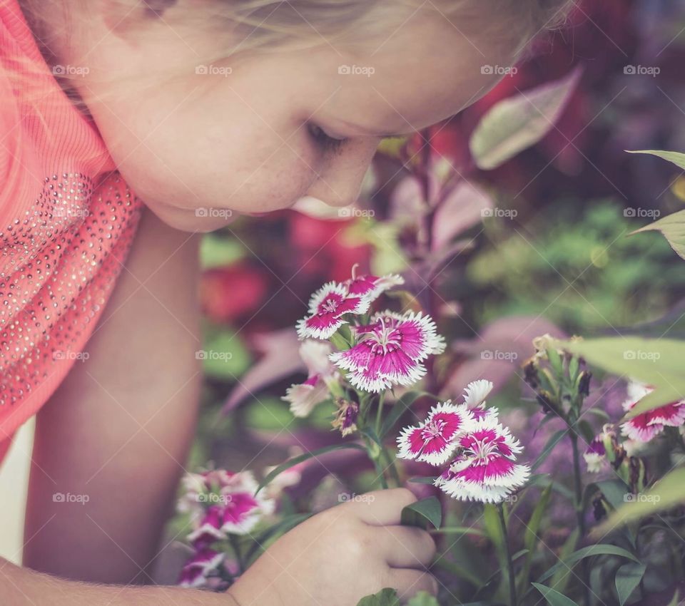 Little girl stopping to Smell the pink flowers