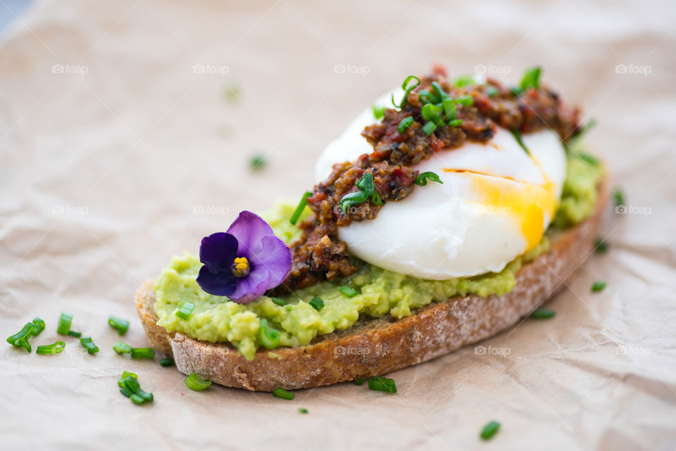 Delicious open sandwich made of avocado, tapenade, pouch-egg on chiabatta