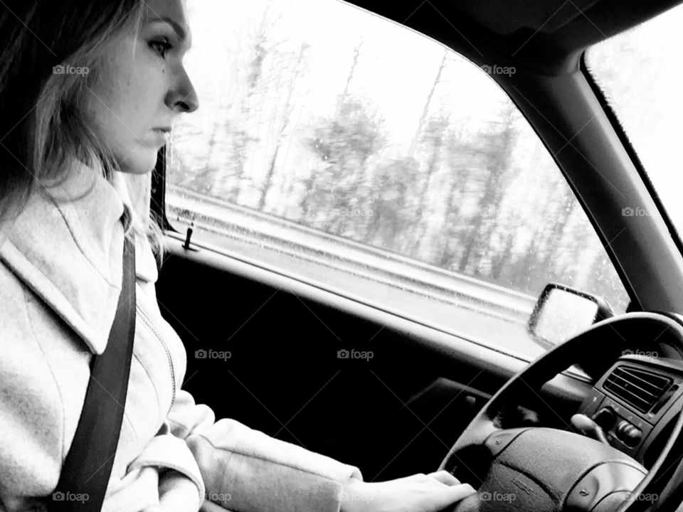 On the road. Woman driving the car, profile view, black&white