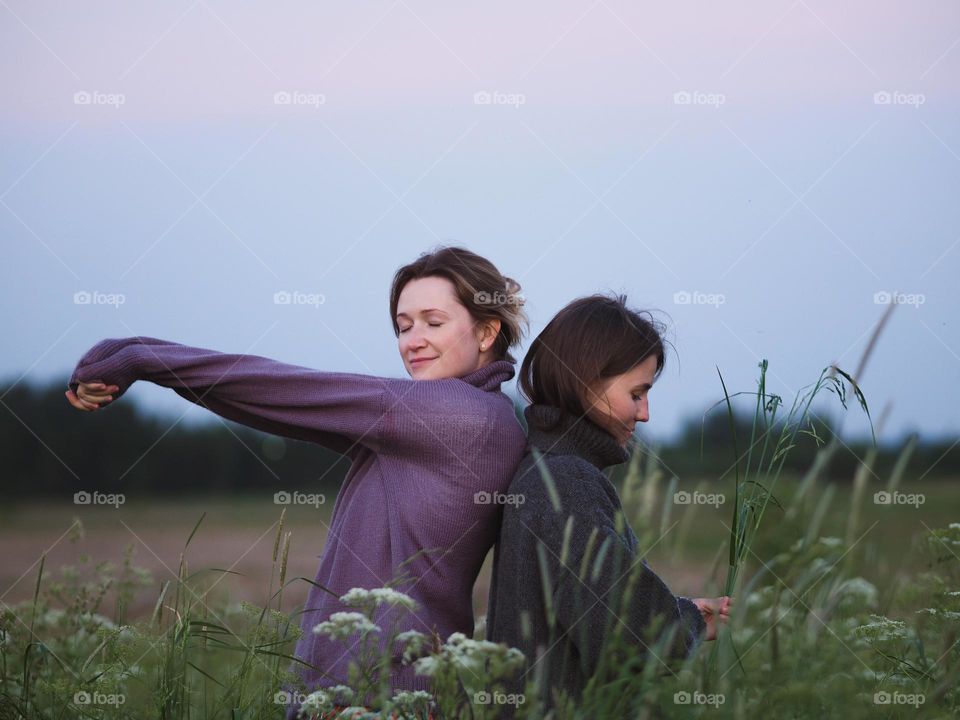 Two young beautiful woman’s standing in field in sunny summer day, portrait of woman 