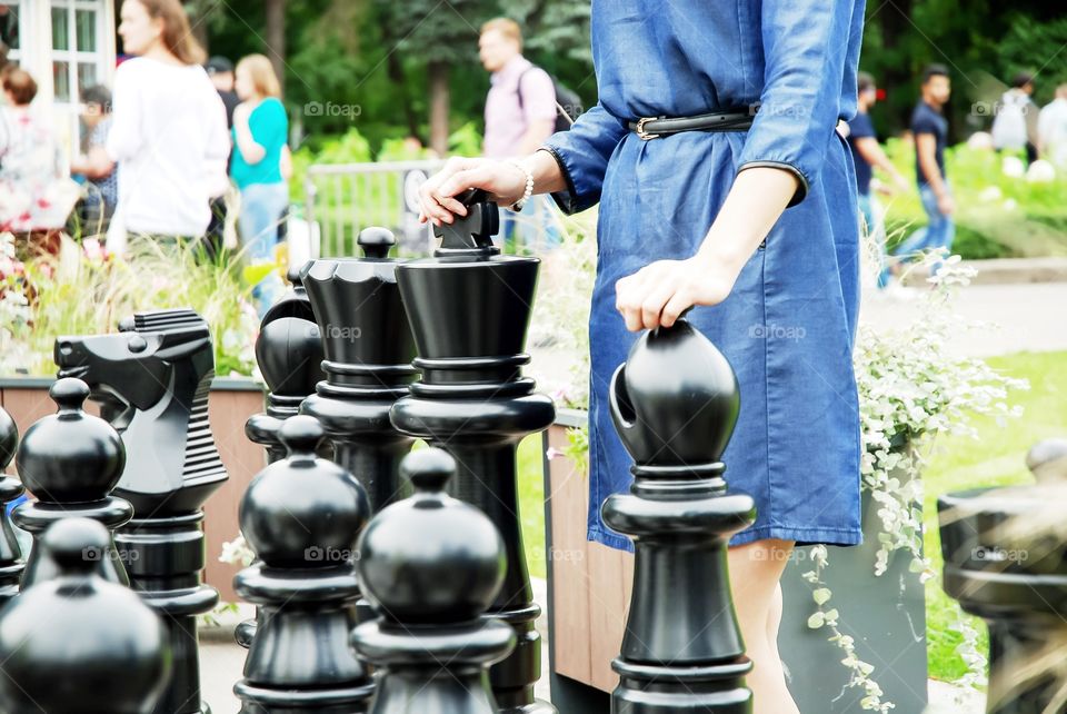 Girl playing large outdoor chess