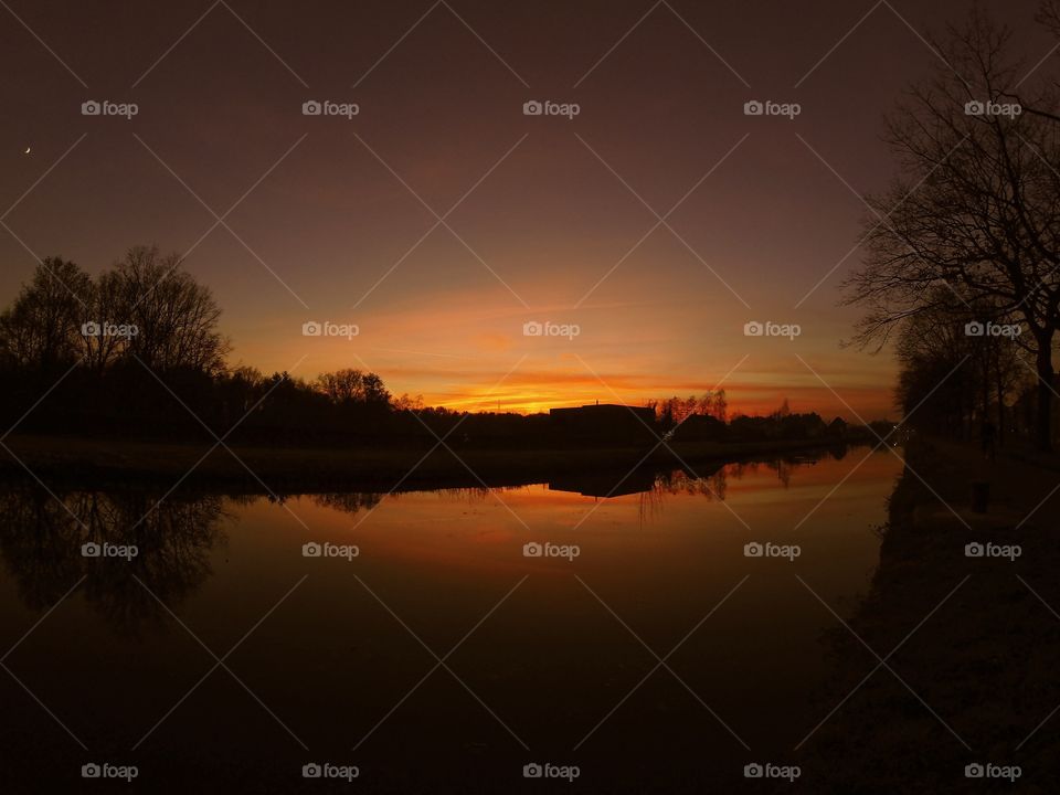 Countryside sunrise showing the colorful sky reflected in the water of the river 