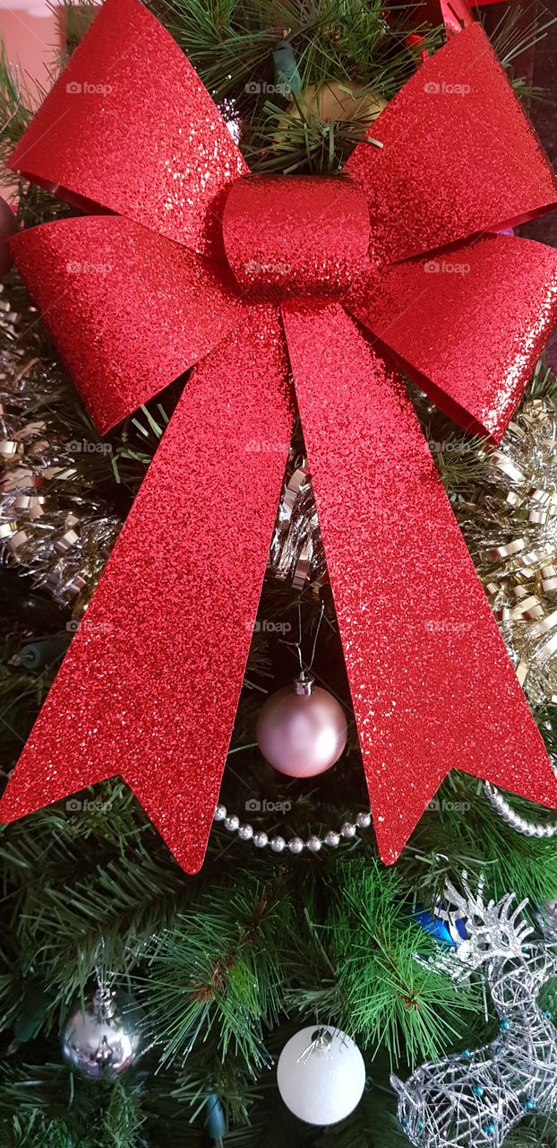 Big and bright red Christmas bow. Love this look on our tree.