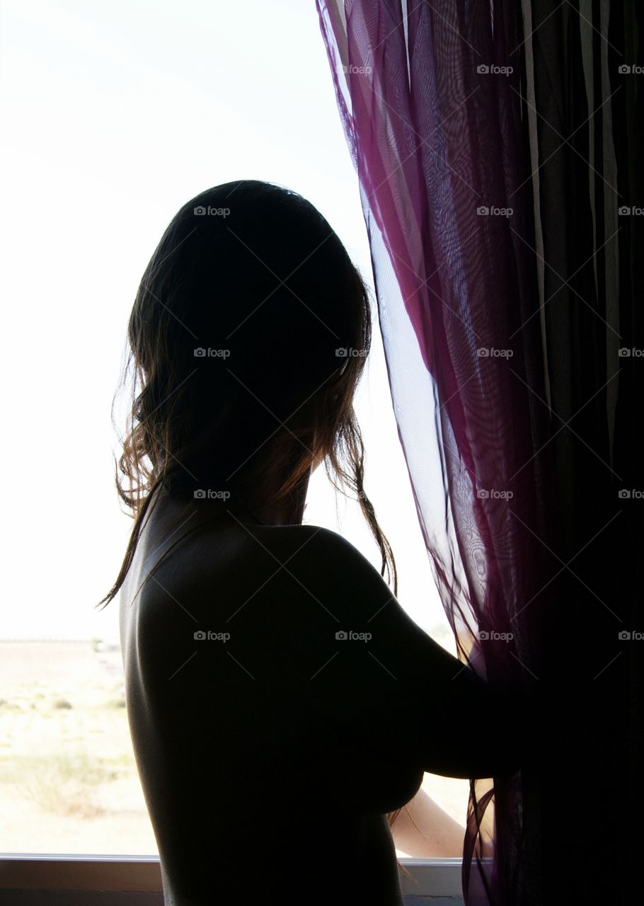 beautiful young woman in the shadows of a window