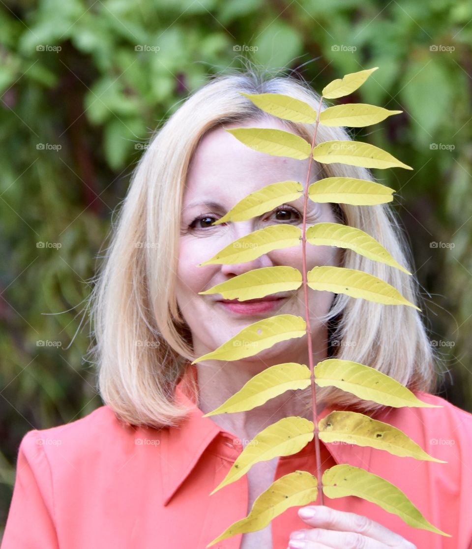 Blonde woman holding a yellow leaf 