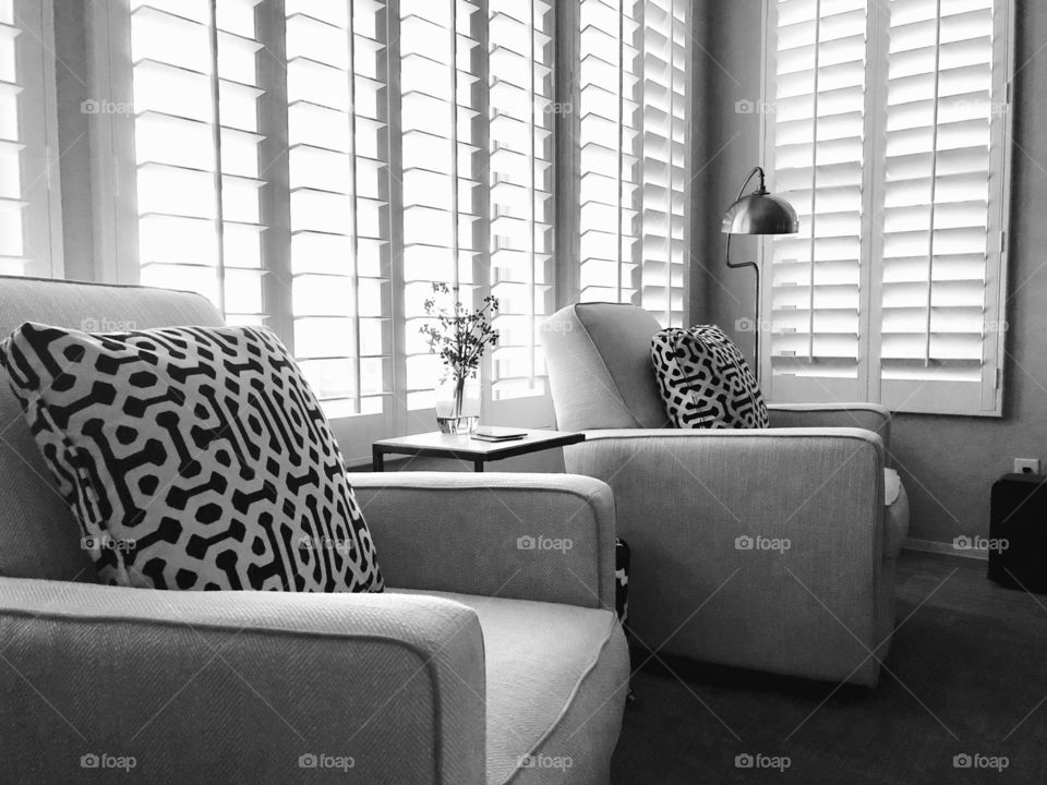 Black and white arm chairs against a wall of white plantation shutters