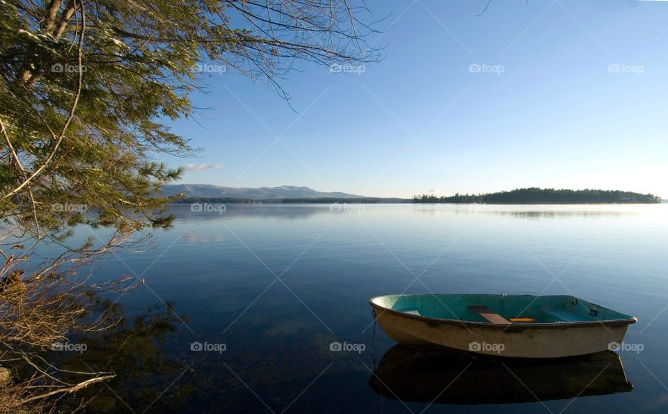 Rowboat sitting on a calm Lake Winnepesaukee with the mountains in the