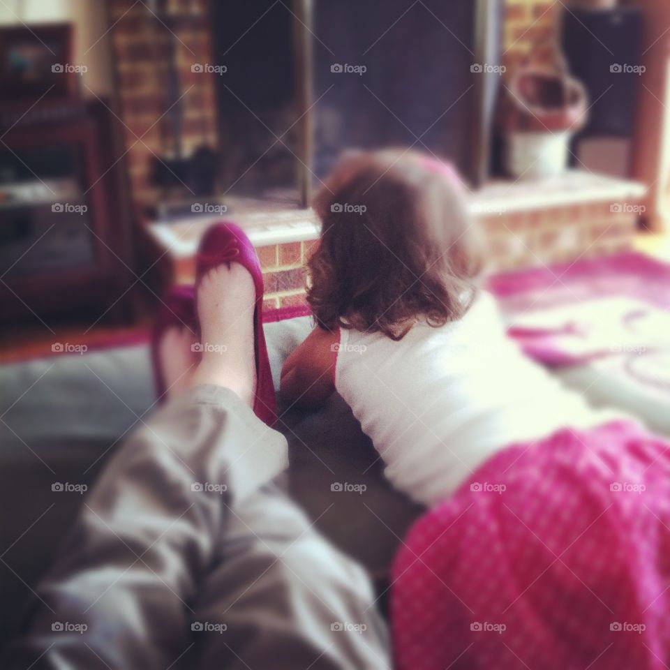 Child in pink tutu watches TV with adult in pink ballet flats