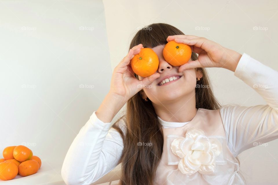 Girl holding oranges on her eyes