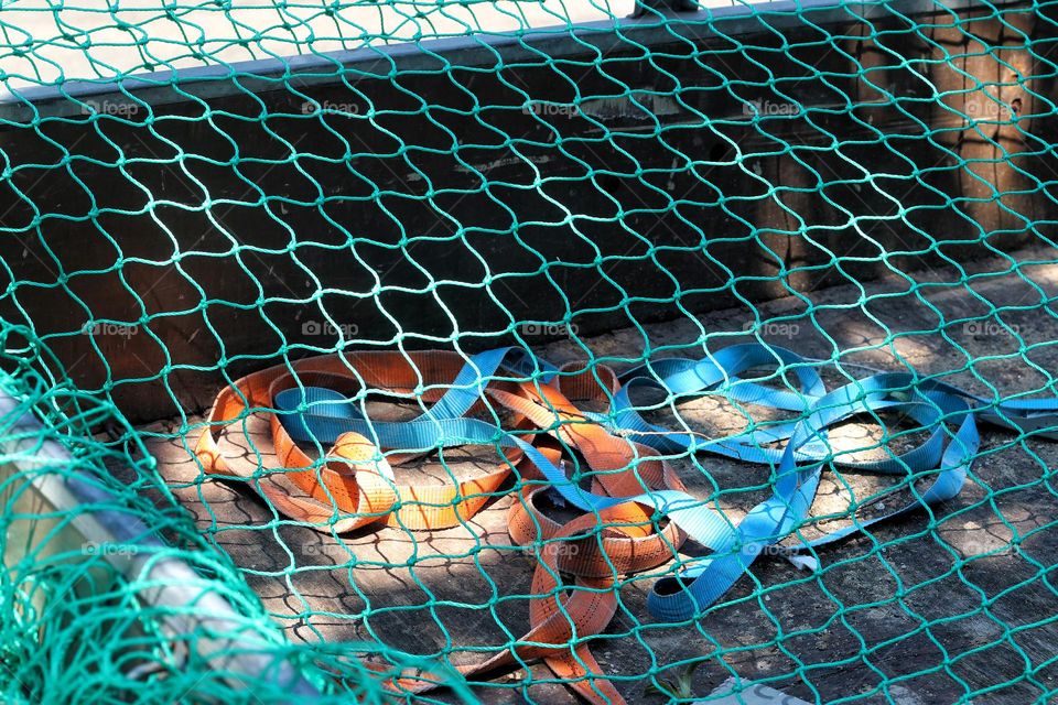 Various colorful belts lie under a green net on a truck bed