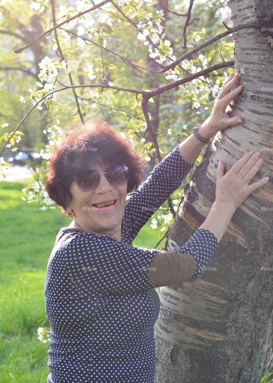 woman smiling and tree spring blooming green background, emotions