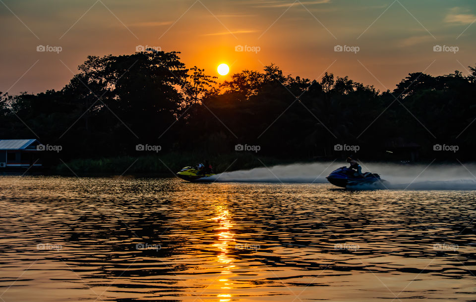 Tourists drive the Jet Ski and the sunset light in Khwae Noi river at Kanchanaburi Thailand .December 2, 2018