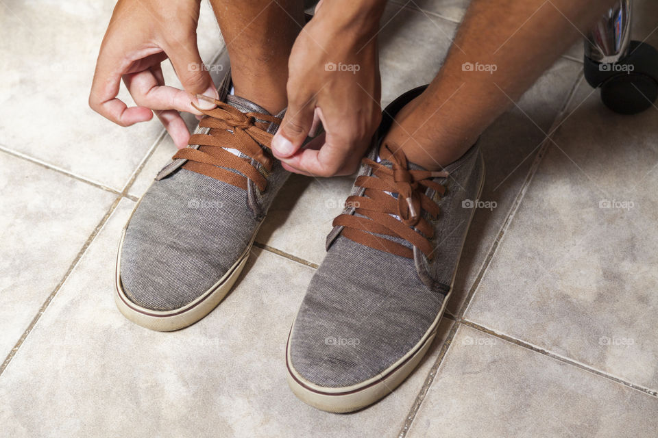Young sportsman tying up tennis before going out to do running exercise in the morning