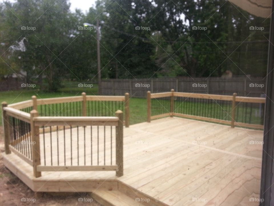 Brand new wooden deck with black spindles and a bump out section that has not been stained yet 