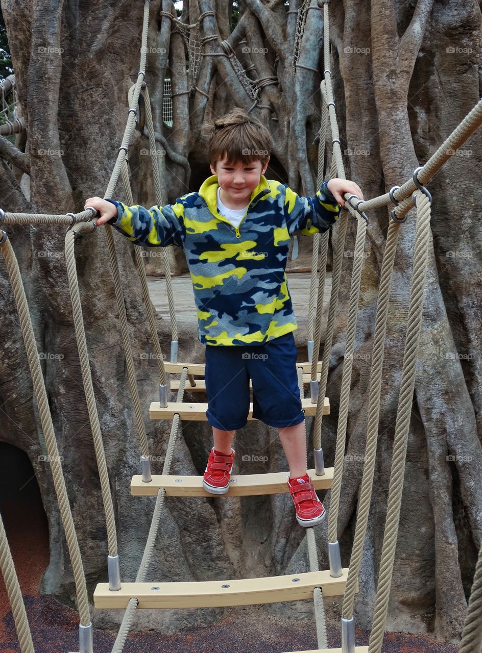 Step By Step. Brave Boy Crossing A Rope Bridge
