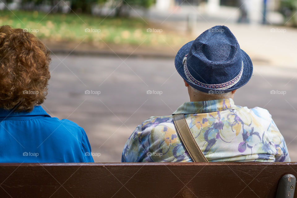 Elderly man with hat sitting in a street bench