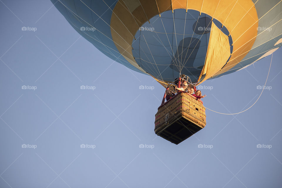 Happy group of women posing in hot air balloon basket on blue sky background